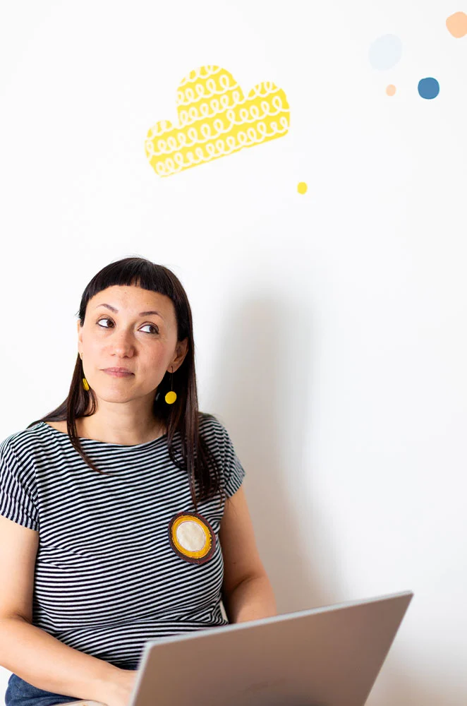 Silvia pensierosa,  seduta con il computer sulle ginocchia. Sopra di lei uno sticker a forma di nuvola gialla
